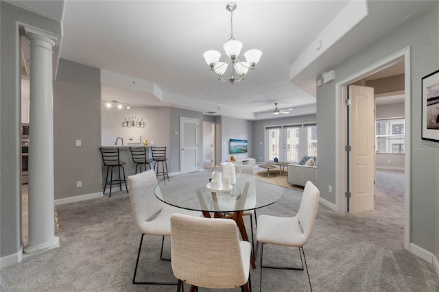 dining room featuring light carpet, ceiling fan with notable chandelier, decorative columns, and bar