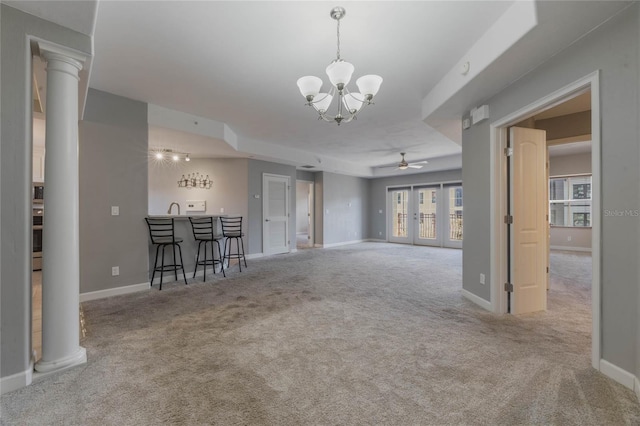 unfurnished living room featuring french doors, light colored carpet, decorative columns, and bar area