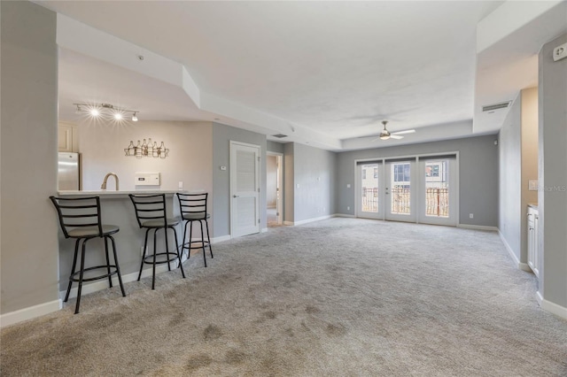 carpeted living room featuring ceiling fan, french doors, and indoor wet bar