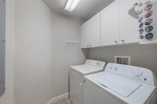 clothes washing area with cabinets, light tile patterned floors, and washer and clothes dryer