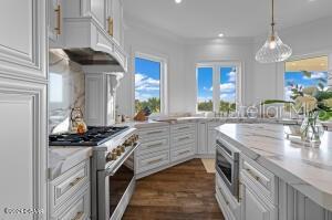 801 N Flagler Ave, Flagler Beach, FL 32136 - kitchen with appliances with stainless steel finishes, decorative light fixtures, white cabinetry, light stone counters, and custom range hood