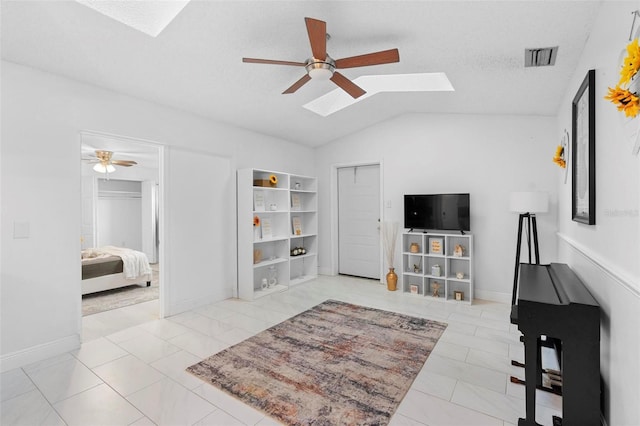 living room with lofted ceiling with skylight, ceiling fan, and a textured ceiling