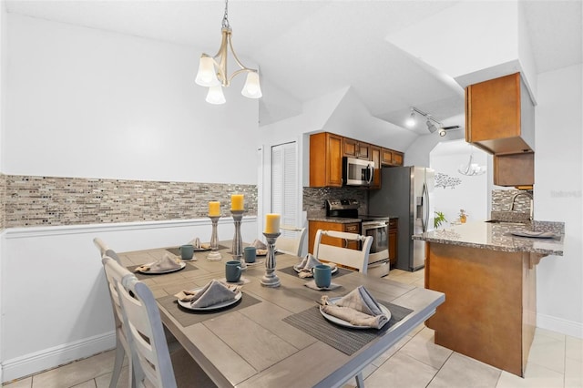 kitchen with sink, backsplash, stainless steel appliances, a notable chandelier, and decorative light fixtures