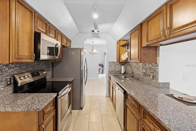 kitchen with light tile patterned flooring, sink, dark stone countertops, stainless steel appliances, and an inviting chandelier