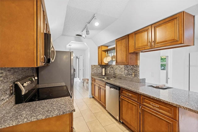 kitchen featuring appliances with stainless steel finishes, lofted ceiling, sink, dark stone counters, and light tile patterned floors