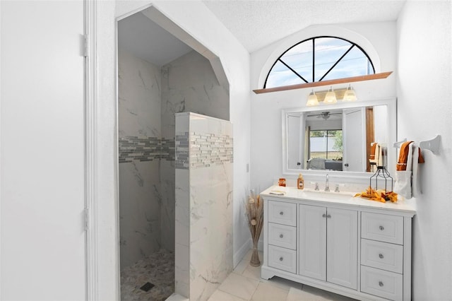 bathroom featuring vanity, lofted ceiling, tiled shower, and a textured ceiling