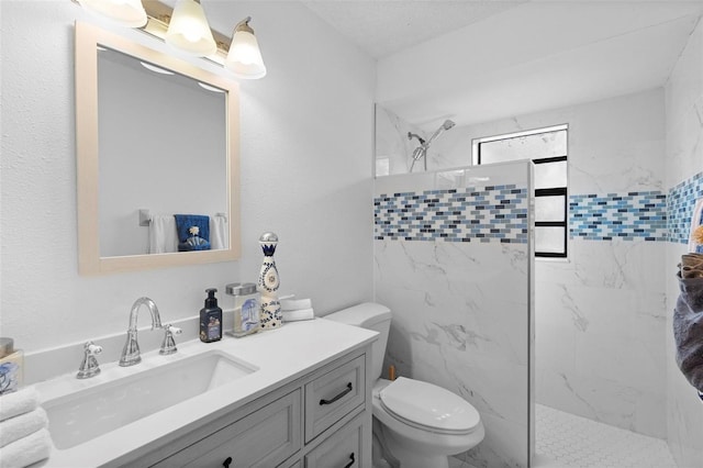 bathroom featuring vanity, a tile shower, and toilet