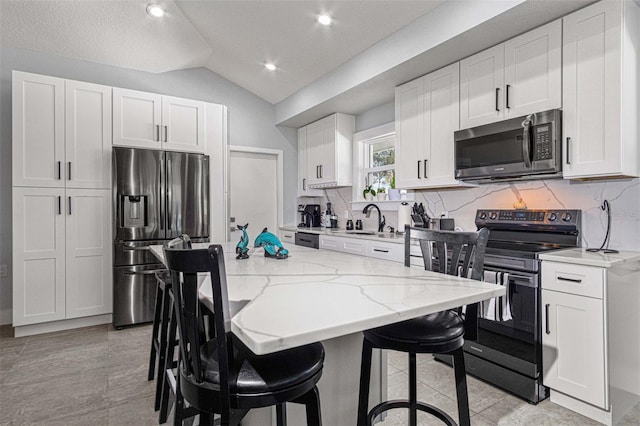 kitchen with a kitchen island, white cabinetry, appliances with stainless steel finishes, and a breakfast bar area