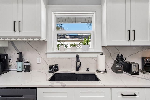 kitchen featuring dishwasher, white cabinetry, light stone countertops, and sink