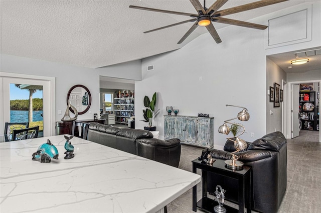 carpeted living room featuring ceiling fan, a water view, lofted ceiling, and a textured ceiling