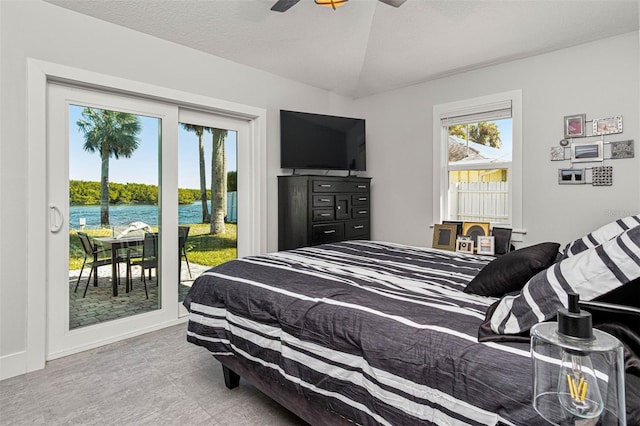 bedroom with ceiling fan, lofted ceiling, access to exterior, and a textured ceiling