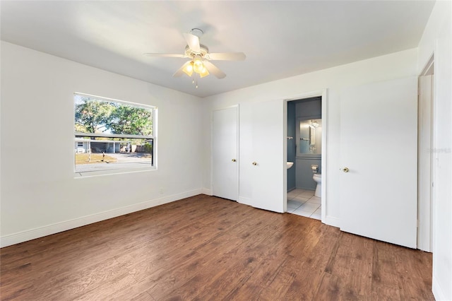 unfurnished bedroom featuring wood-type flooring, ensuite bathroom, and ceiling fan