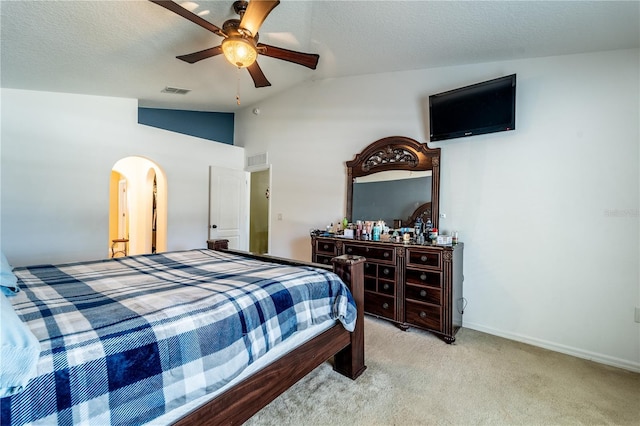 bedroom with vaulted ceiling, light carpet, ceiling fan, and a textured ceiling