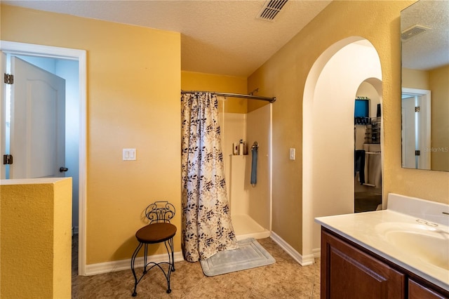 bathroom featuring vanity, a textured ceiling, and walk in shower