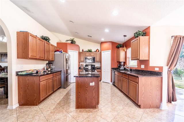 kitchen featuring sink, a center island, vaulted ceiling, hanging light fixtures, and appliances with stainless steel finishes