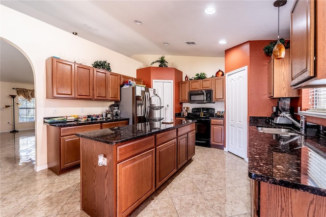 kitchen with sink, a center island, pendant lighting, dark stone counters, and black appliances