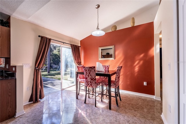 tiled dining room featuring vaulted ceiling and a textured ceiling