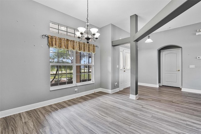 unfurnished dining area with lofted ceiling, hardwood / wood-style floors, and a chandelier