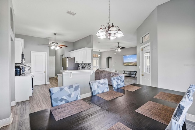 dining area with ceiling fan with notable chandelier and light wood-type flooring