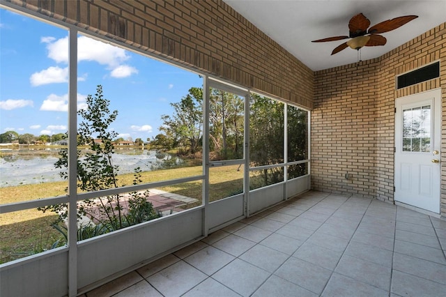 unfurnished sunroom featuring a water view, ceiling fan, and plenty of natural light