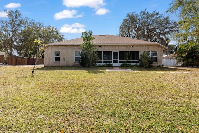 rear view of property featuring a lawn and a sunroom