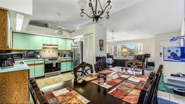 dining space featuring ceiling fan with notable chandelier and a textured ceiling