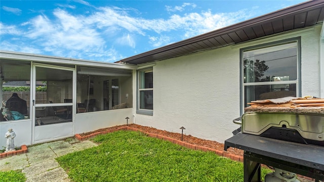 view of side of home with a lawn and a sunroom