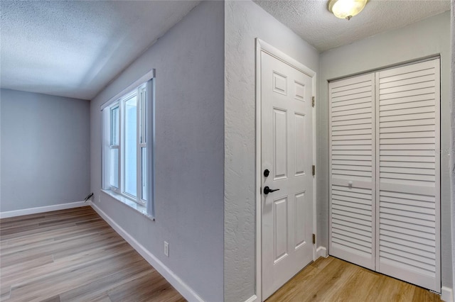 foyer entrance with light hardwood / wood-style flooring and a textured ceiling