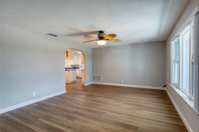 empty room featuring ceiling fan, wood-type flooring, and a textured ceiling