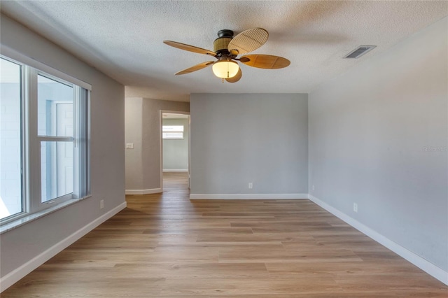 empty room featuring ceiling fan, light hardwood / wood-style flooring, and a textured ceiling