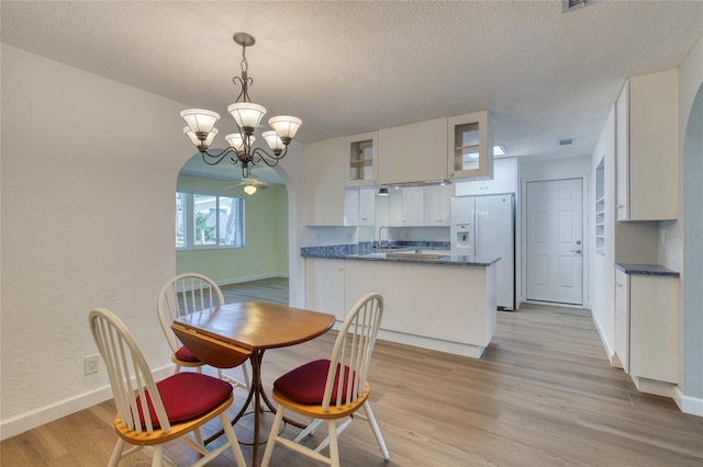 dining area with a notable chandelier, sink, a textured ceiling, and light wood-type flooring