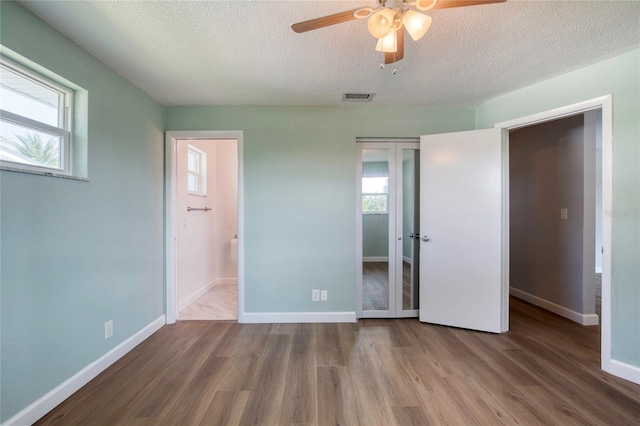 unfurnished bedroom with multiple windows, wood-type flooring, and french doors