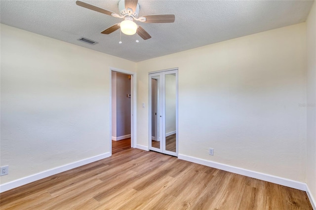 unfurnished bedroom with ceiling fan, light hardwood / wood-style floors, a closet, and a textured ceiling