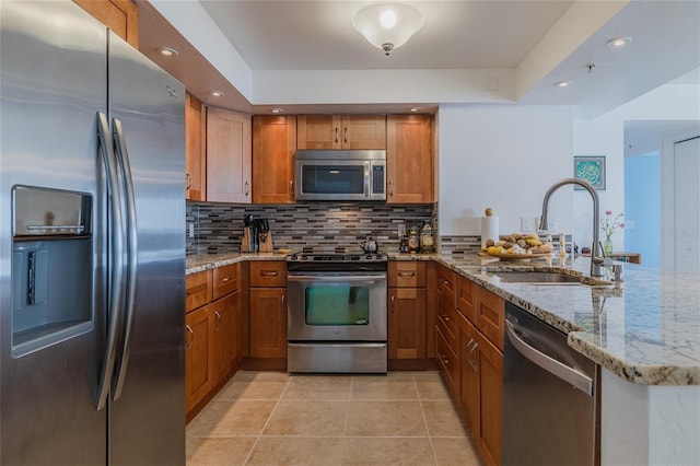 kitchen featuring sink, backsplash, stainless steel appliances, and light stone countertops