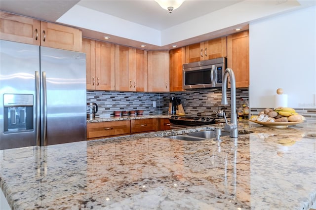 kitchen with light stone counters, sink, tasteful backsplash, and appliances with stainless steel finishes