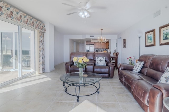 tiled living room with ceiling fan with notable chandelier