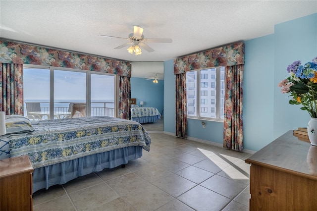 tiled bedroom featuring multiple windows, a textured ceiling, and a water view