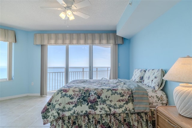 tiled bedroom featuring ceiling fan, access to outside, a textured ceiling, and a water view