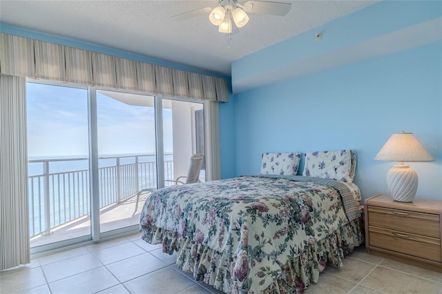 tiled bedroom featuring ceiling fan, access to outside, a textured ceiling, and a water view