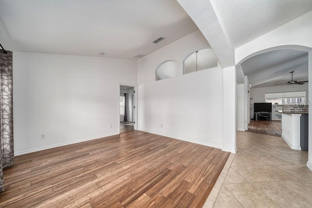 unfurnished living room with lofted ceiling, ceiling fan, and light wood-type flooring