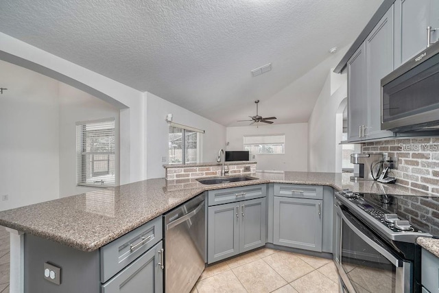 kitchen featuring stainless steel appliances, sink, gray cabinets, and kitchen peninsula