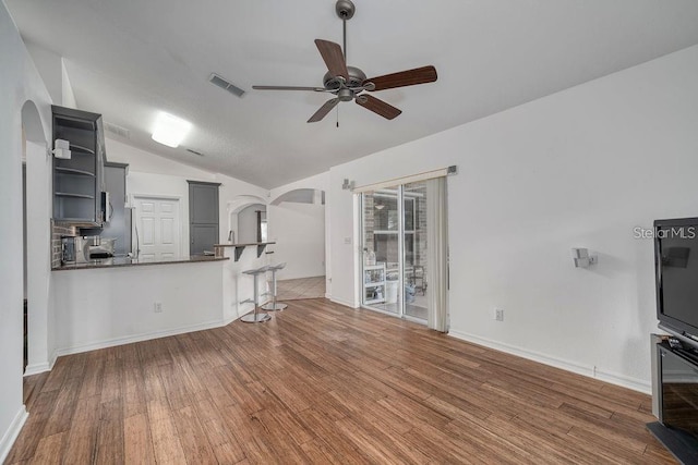 unfurnished living room with vaulted ceiling, dark wood-type flooring, and ceiling fan