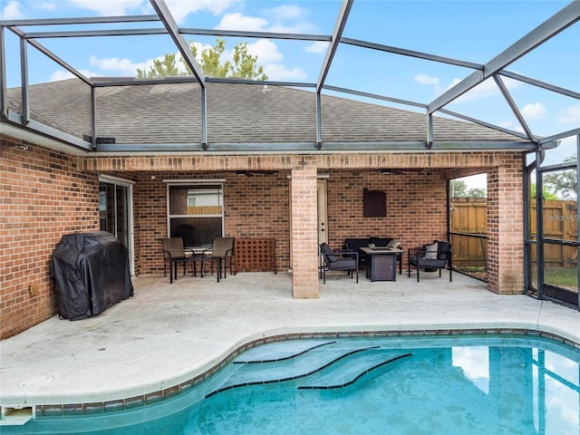 view of pool with grilling area, glass enclosure, and a patio