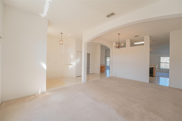 spare room with an inviting chandelier, light colored carpet, and a textured ceiling