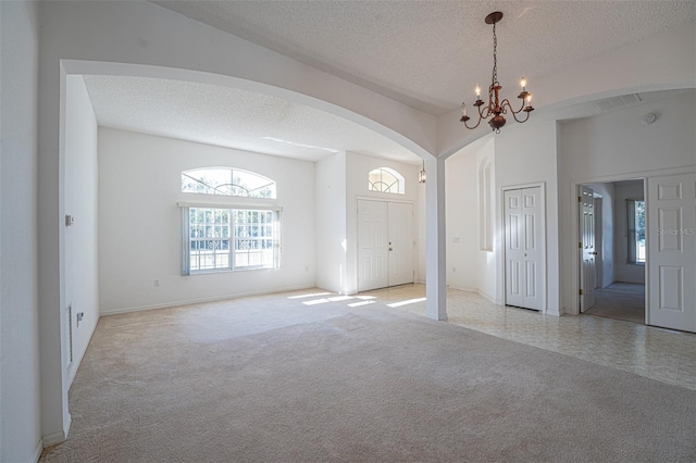 foyer featuring a high ceiling, light colored carpet, a notable chandelier, and a textured ceiling