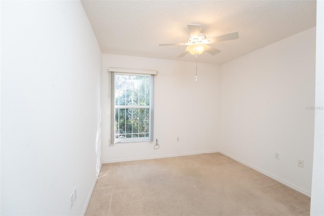 empty room with ceiling fan, light colored carpet, and a textured ceiling