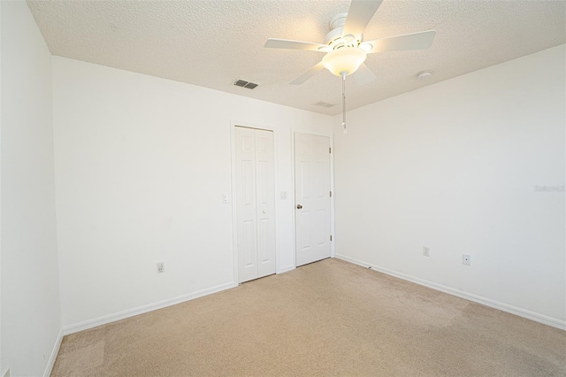 carpeted empty room featuring ceiling fan and a textured ceiling