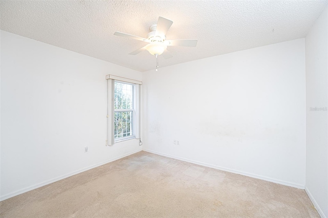 spare room featuring light colored carpet, a textured ceiling, and ceiling fan