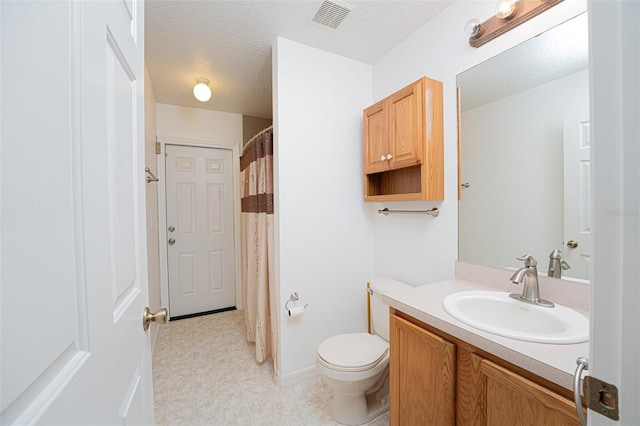 bathroom with vanity, toilet, and a textured ceiling