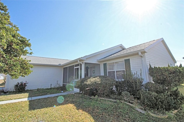 single story home featuring a front lawn and a sunroom